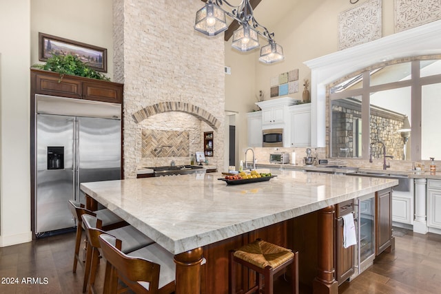 kitchen featuring a towering ceiling, built in appliances, and white cabinetry