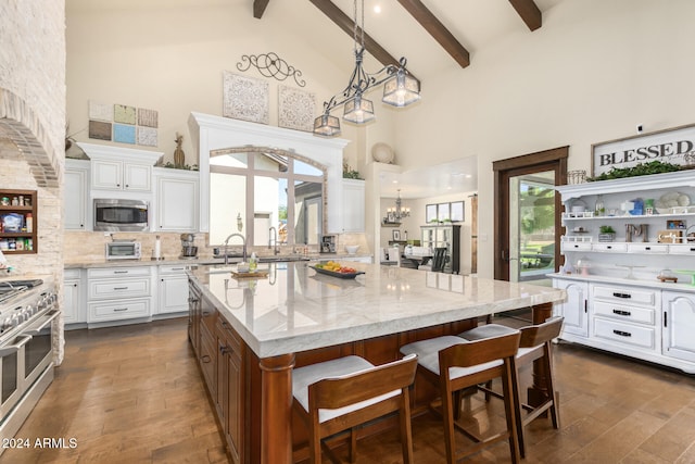 kitchen featuring beamed ceiling, high vaulted ceiling, white cabinetry, stainless steel appliances, and a center island