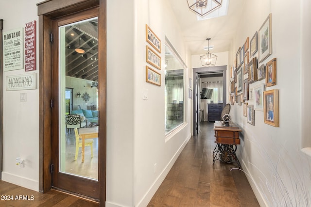 hall with vaulted ceiling, dark hardwood / wood-style floors, and a chandelier