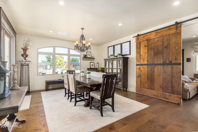 dining space featuring an inviting chandelier, a barn door, and dark wood-type flooring