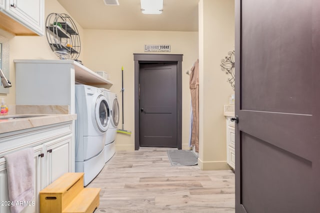 washroom featuring washing machine and clothes dryer, cabinets, light hardwood / wood-style flooring, and sink