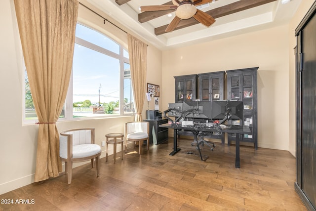 office space featuring a raised ceiling, hardwood / wood-style flooring, and ceiling fan