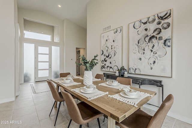 dining room featuring baseboards, visible vents, high vaulted ceiling, and light tile patterned floors
