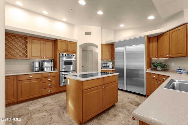 kitchen featuring a towering ceiling, appliances with stainless steel finishes, a kitchen island, and sink