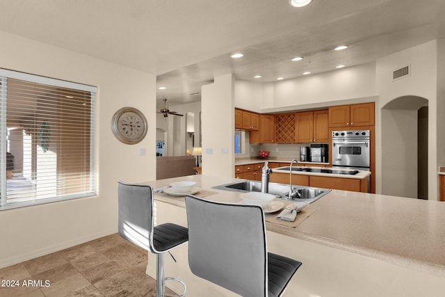 kitchen featuring oven, stovetop, sink, and a kitchen breakfast bar