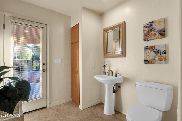 bathroom with toilet, sink, and tile patterned floors