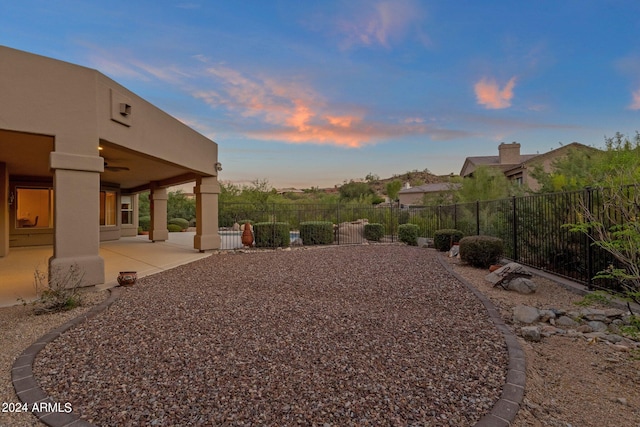 yard at dusk featuring a patio area and ceiling fan