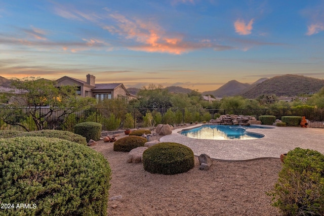 pool at dusk with a jacuzzi, a patio area, and a mountain view