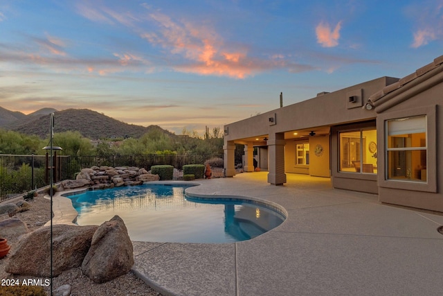 pool at dusk with a patio area and a mountain view