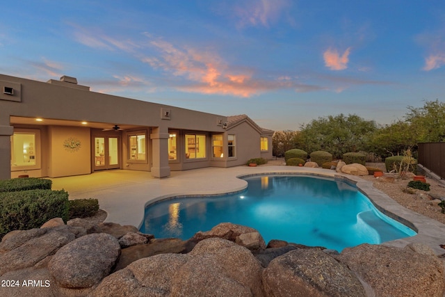 pool at dusk with a patio area and ceiling fan