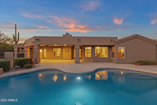 pool at dusk featuring a patio