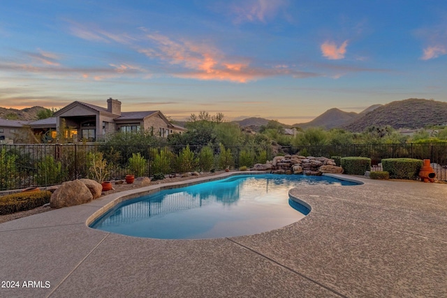 pool at dusk featuring a mountain view and a patio