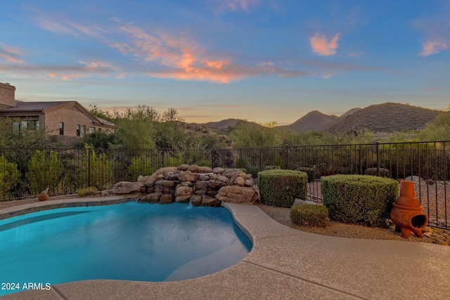 pool at dusk featuring a mountain view