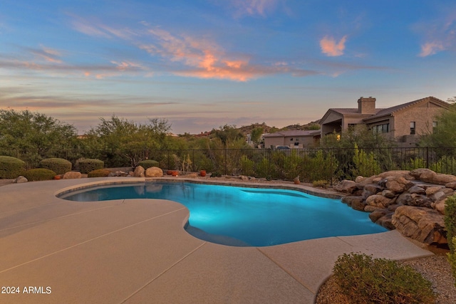 pool at dusk featuring a patio