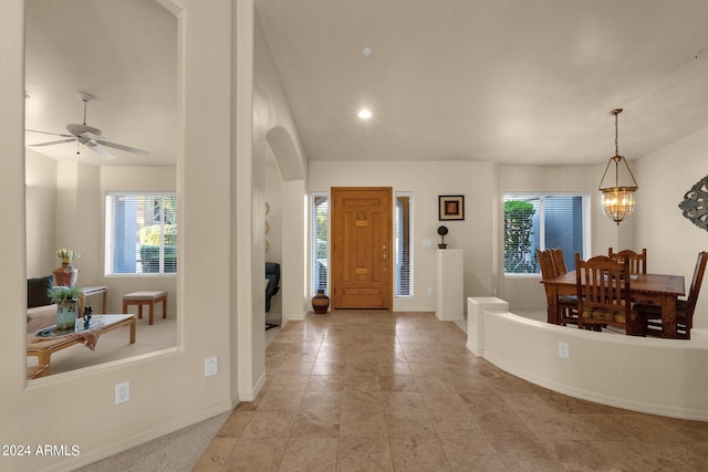 foyer entrance with ceiling fan with notable chandelier