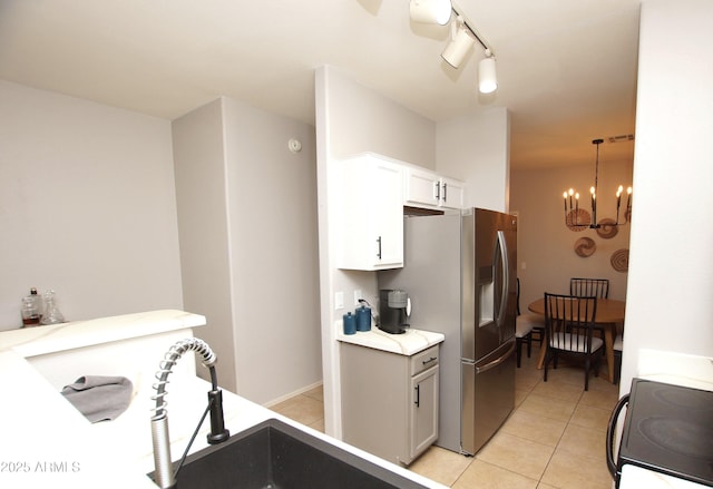 kitchen featuring pendant lighting, a chandelier, light tile patterned floors, range with electric cooktop, and white cabinets