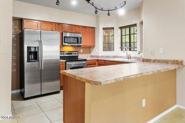 kitchen with rail lighting, stainless steel appliances, sink, kitchen peninsula, and light tile patterned floors