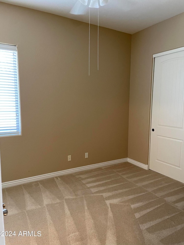 spare room with a wealth of natural light, ceiling fan, and carpet floors