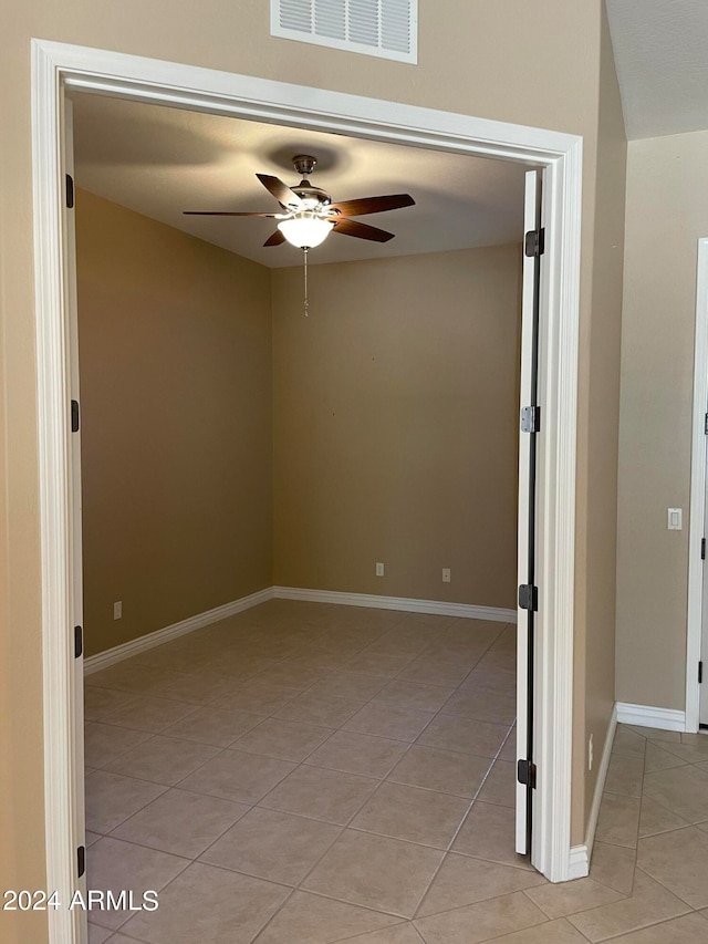 tiled spare room with ceiling fan