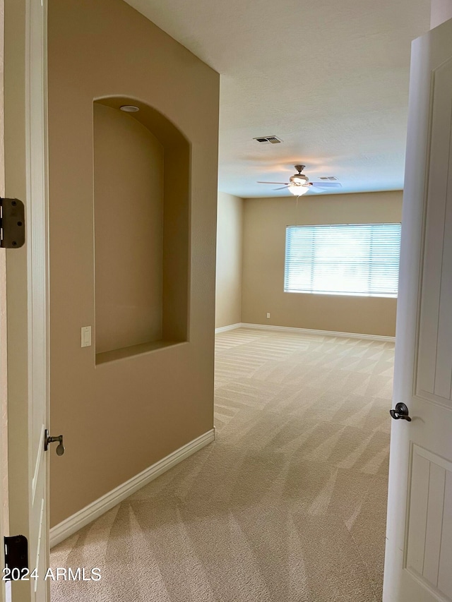 unfurnished room with ceiling fan and carpet