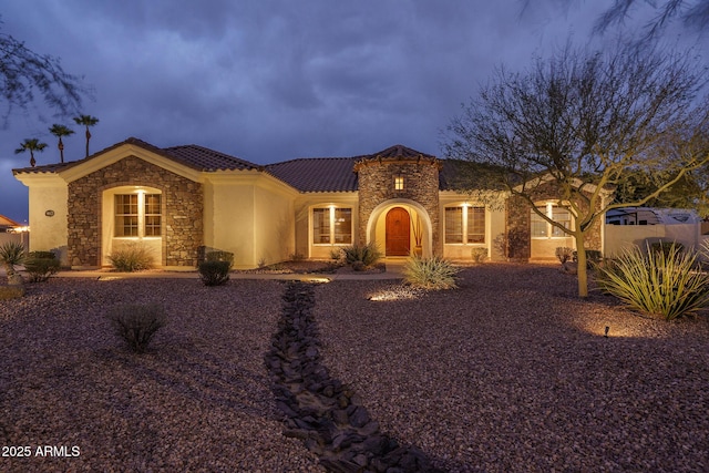 mediterranean / spanish-style home featuring stone siding, a tiled roof, and stucco siding