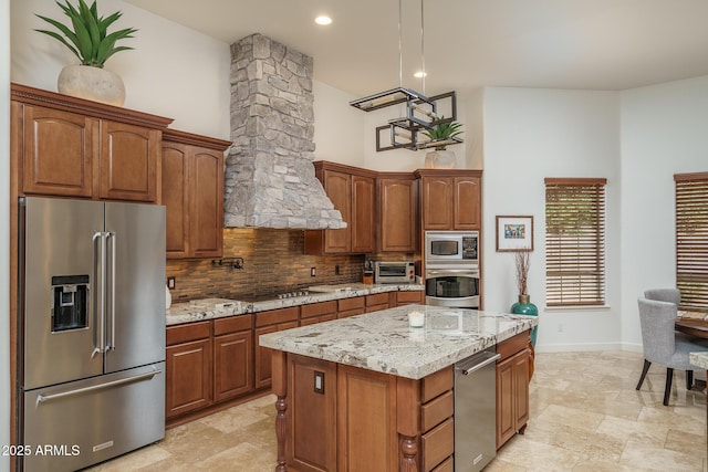 kitchen with decorative columns, a center island, light stone countertops, stainless steel appliances, and backsplash