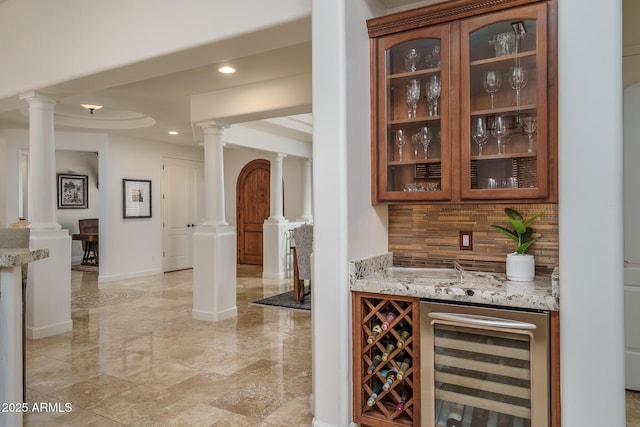 bar with beverage cooler, decorative columns, and backsplash