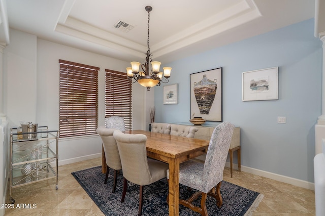 dining area featuring a chandelier, a raised ceiling, visible vents, and baseboards