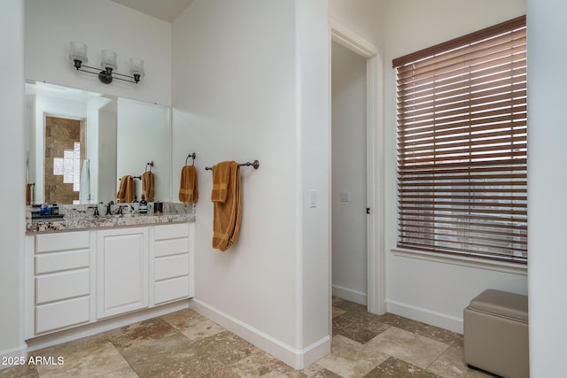 bathroom featuring stone finish flooring, vanity, and baseboards