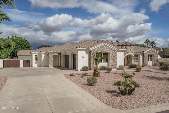 mediterranean / spanish-style house featuring a garage, stone siding, concrete driveway, and a tile roof