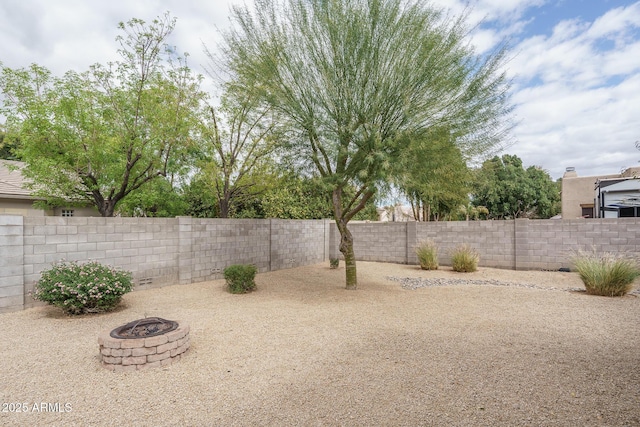 view of yard featuring a fenced backyard and a fire pit