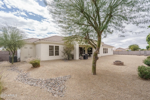 back of property with a fire pit, central AC, fence, stucco siding, and a patio area