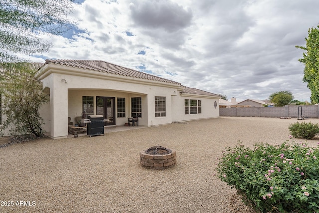 rear view of house featuring an outdoor fire pit, a patio, a tile roof, fence, and stucco siding