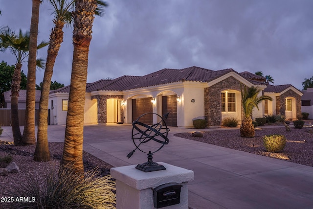 mediterranean / spanish-style house with stucco siding, an attached garage, stone siding, driveway, and a tiled roof