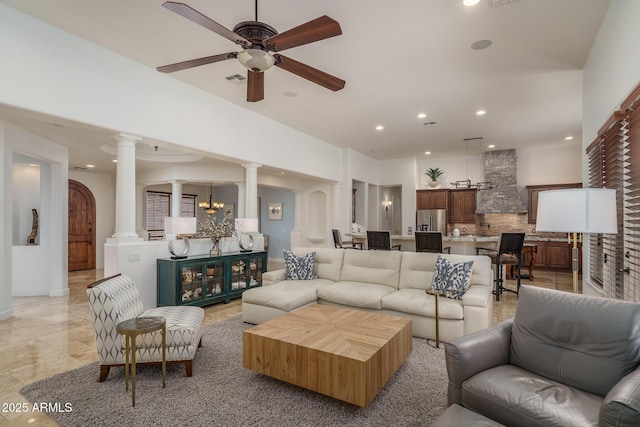 living area featuring recessed lighting, decorative columns, arched walkways, and ceiling fan with notable chandelier