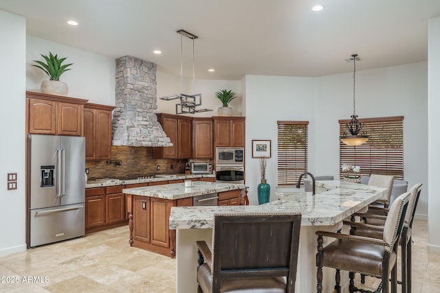 kitchen with a kitchen island with sink, a toaster, appliances with stainless steel finishes, tasteful backsplash, and pendant lighting