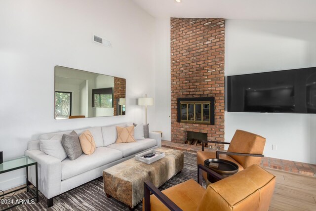 living room featuring lofted ceiling, hardwood / wood-style floors, and a fireplace