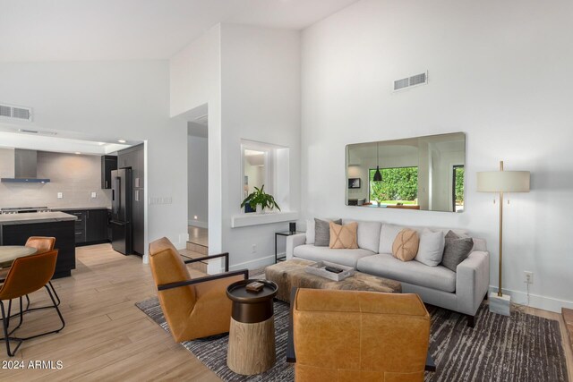 living room featuring high vaulted ceiling and light hardwood / wood-style floors