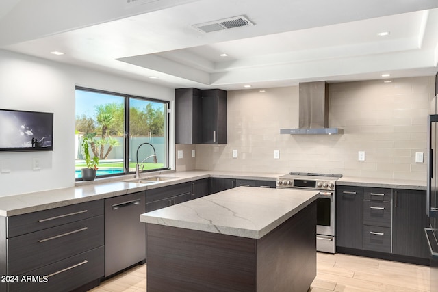 kitchen with a kitchen island, wall chimney exhaust hood, appliances with stainless steel finishes, light hardwood / wood-style floors, and sink