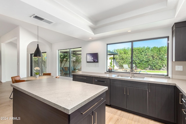 kitchen featuring a center island, decorative light fixtures, light wood-type flooring, sink, and stainless steel dishwasher