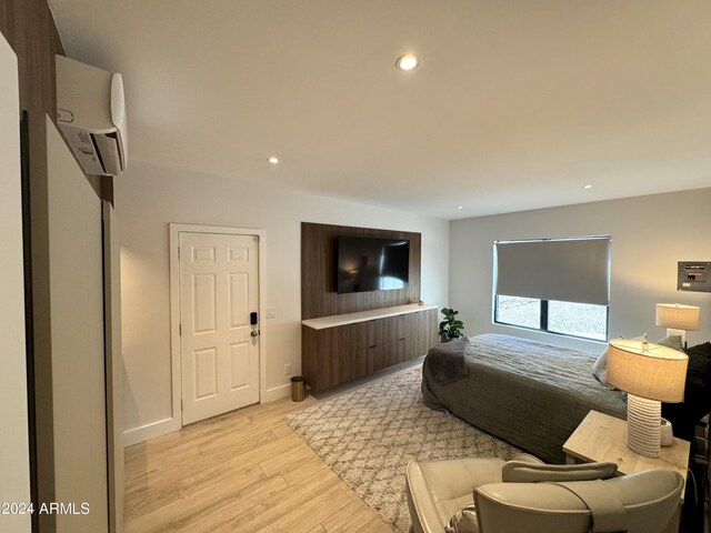 bedroom with a wall mounted AC and light hardwood / wood-style flooring