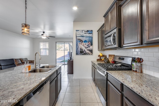 kitchen featuring stainless steel appliances, decorative light fixtures, sink, and light stone counters