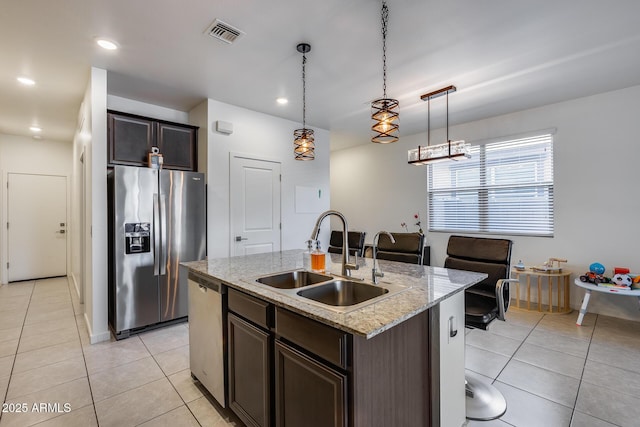 kitchen with appliances with stainless steel finishes, hanging light fixtures, an island with sink, dark brown cabinetry, and sink