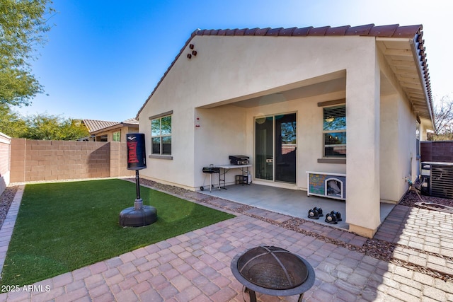 back of house featuring an outdoor fire pit, a yard, central air condition unit, and a patio