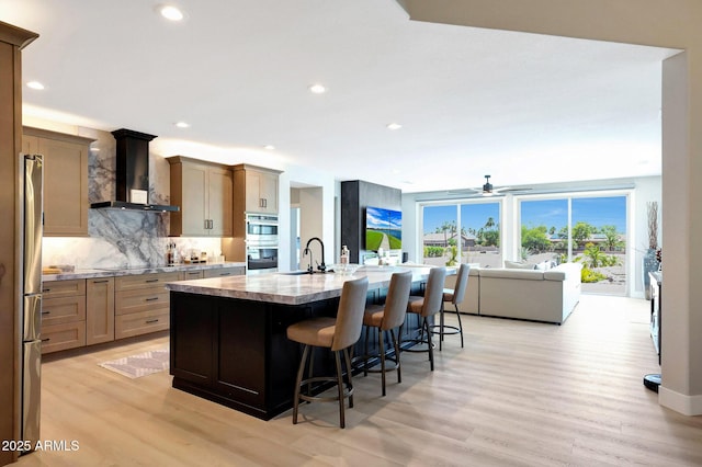 19745 N Mountain Sage Ln, Surprise, AZ 85374 - kitchen with wall chimney range hood, appliances with stainless steel finishes, a kitchen breakfast bar, light wood-style floors, and open floor plan