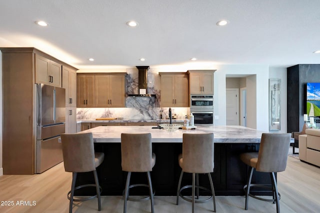 19745 N Mountain Sage Ln, Surprise, AZ 85374 - kitchen featuring appliances with stainless steel finishes, wall chimney range hood, decorative backsplash, light wood-type flooring, and recessed lighting