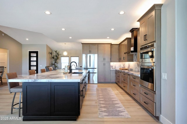 19745 N Mountain Sage Ln, Surprise, AZ 85374 - kitchen with appliances with stainless steel finishes, a breakfast bar, wall chimney exhaust hood, a spacious island, and recessed lighting