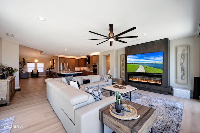 19745 N Mountain Sage Ln, Surprise, AZ 85374 - living room with a large fireplace, light wood-style floors, recessed lighting, and ceiling fan