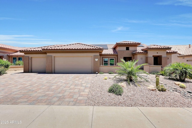 19745 N Mountain Sage Ln, Surprise, AZ 85374 - view of front facade with an attached garage, stucco siding, solar panels, decorative driveway, and a tile roof