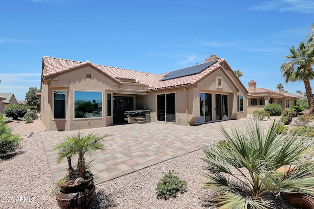 19745 N Mountain Sage Ln, Surprise, AZ 85374 - back of property featuring stucco siding, solar panels, a patio area, and a hot tub